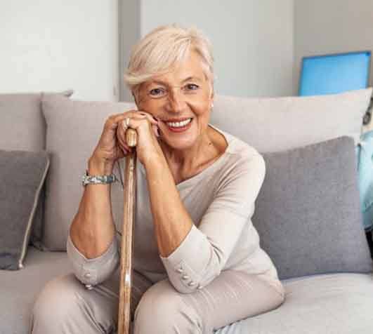 an older woman smiling and holding her walking cane