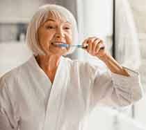 an older woman brushing her teeth in the morning