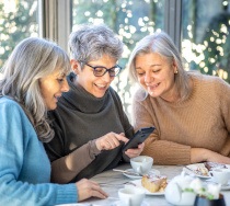 Group of friends smiling while looking at phone at restaurant